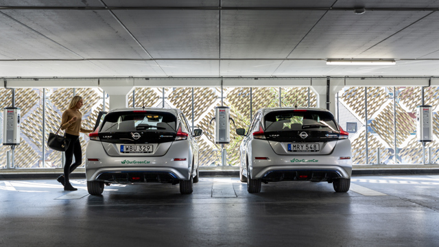 Två elbilar från bilpoolen står parkerade och laddar i ett garage. 
