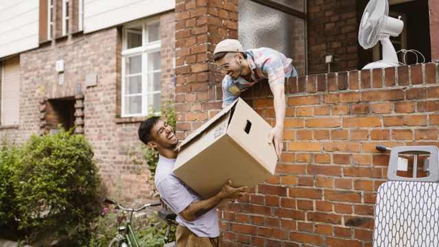 Två yngre män hjälps åt att flytta in.