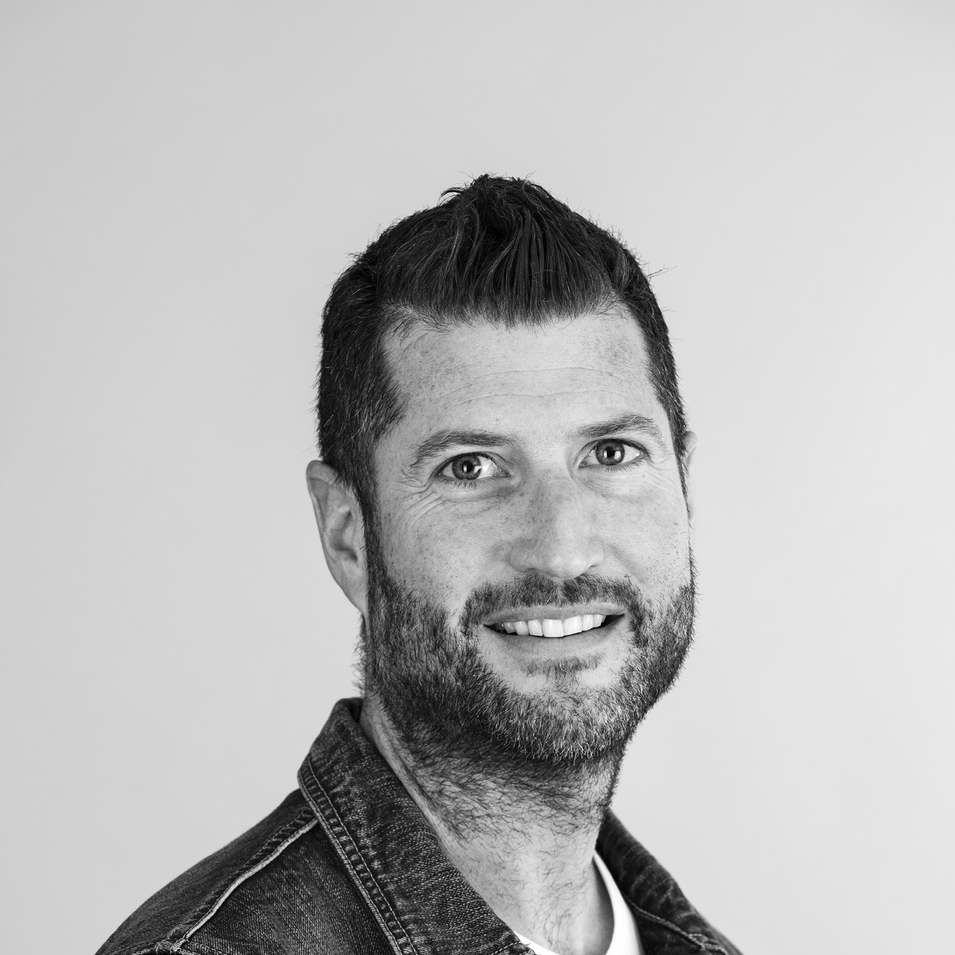 Porträttbild i svartvitt på en mörkhårig leende man. 