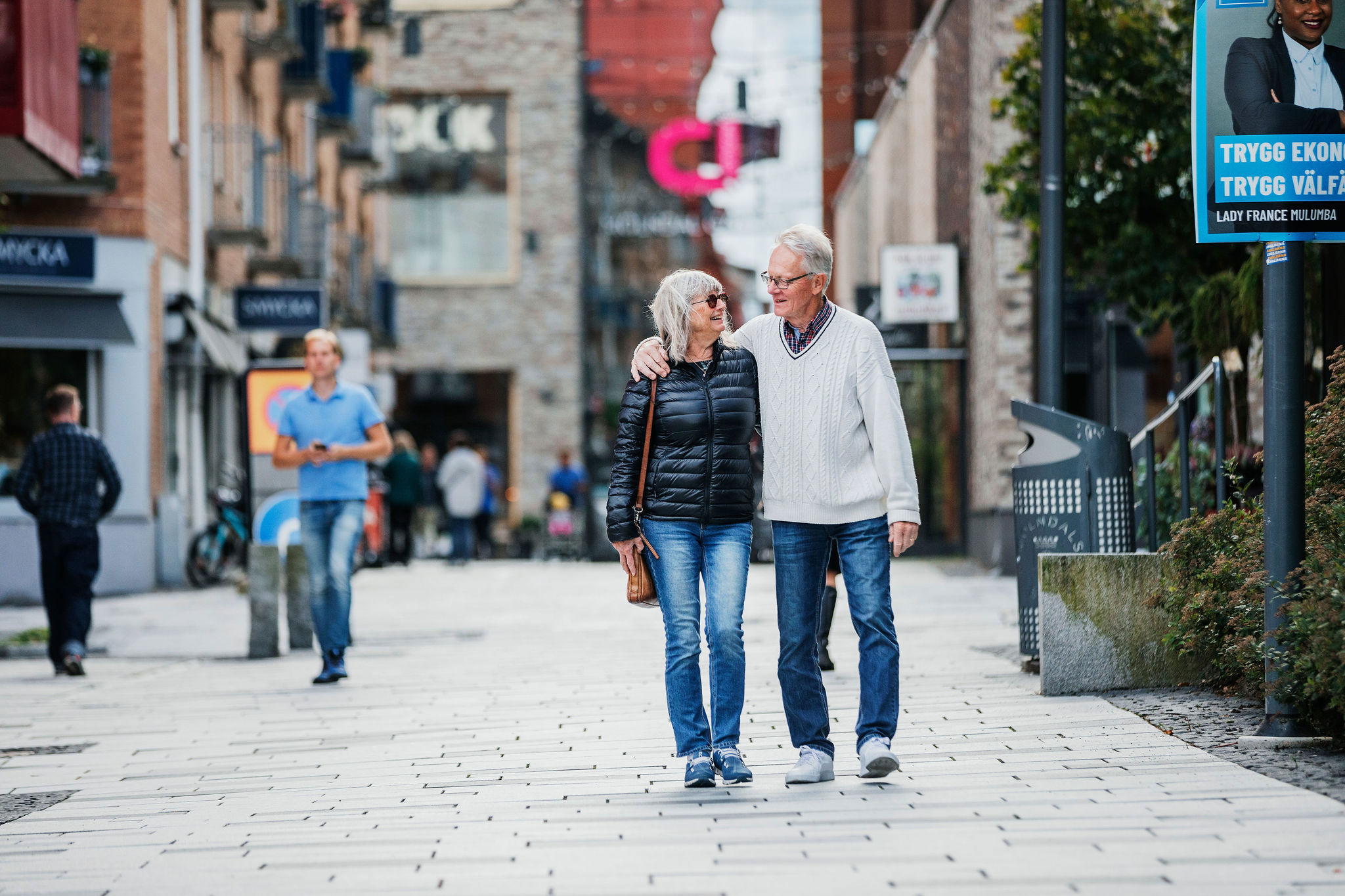 Medelålders par njuter och spatserar i Mölndals innerstad genom att hålla om varandra.