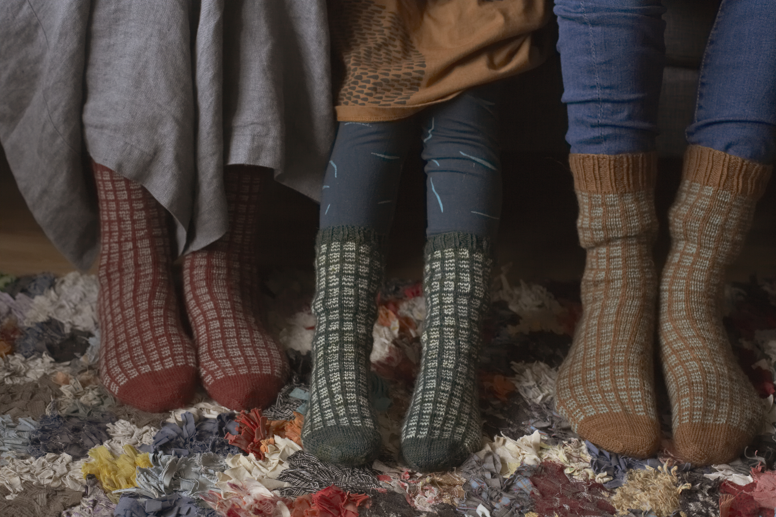 Närbild på tre par fötter med olika sockar som illustrerar en känsla av att det är kallt. 