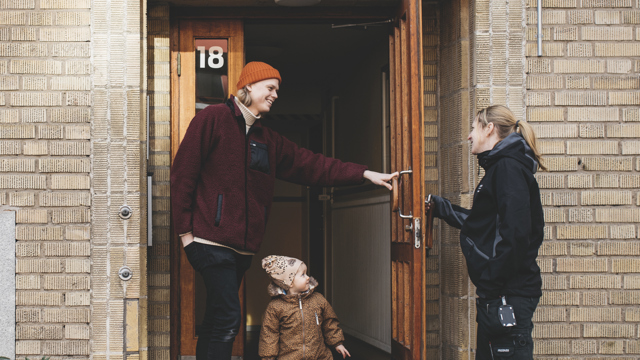 En personal från Mölndalsbostäder möter en hyresgäst med barn i entrén till Mölndalsbostäders flerfamiljshus. 