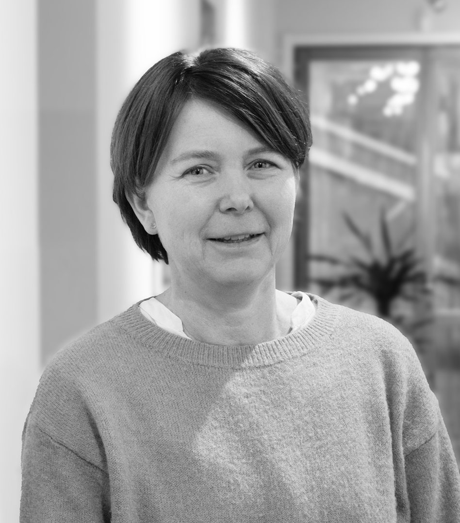 Porträttbild i svartvitt på en korthårig leende kvinna. 